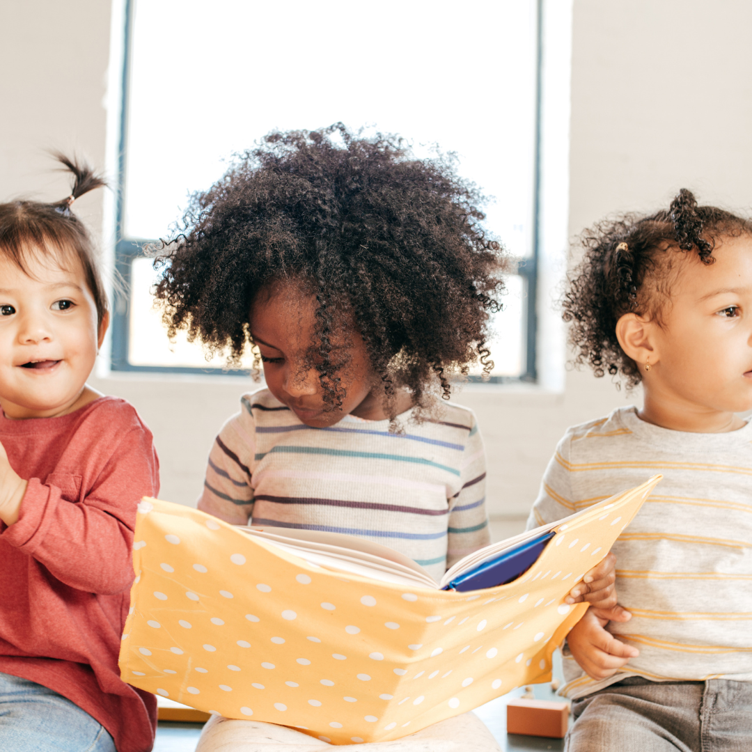 Toddlers sitting and holding a book