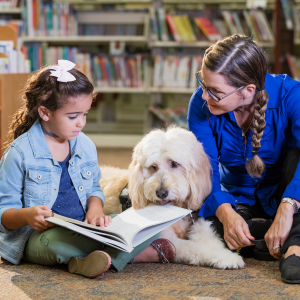 Children reading a book to a dog