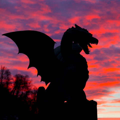 Silhouette of dragon with purple and pink sky.