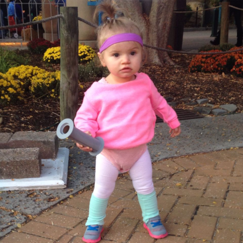 Toddler wearing 80's exercise outfit holding a fake dumbbell. Utterly hilarious.