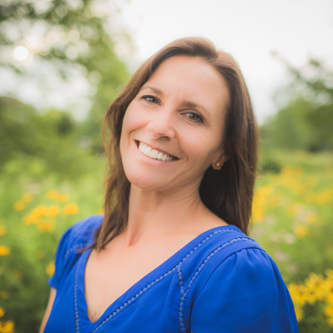 Author/Illustrator photograph of Amy Nielander with blue shirt, green and yellow nature setting behind her.  