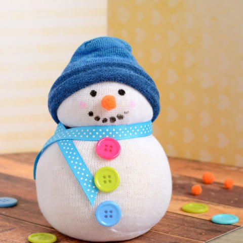 Small snowman with a ribbon scarf and blue hat