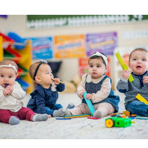 four babies playing on the ground with toys 