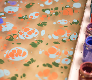 An example of fabric marbling art next to jars of paint